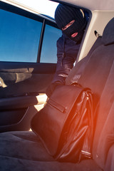 Robber in black mask stealing bag from back seat