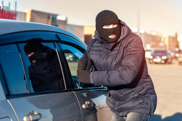 Thief trying to break into car with screwdriver