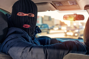 Car thief in black robbery mask driving auto