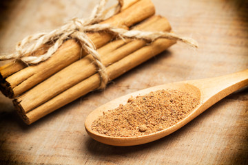 Canela en rama y en polvo sobre tabla de madera rústica. Vista superior