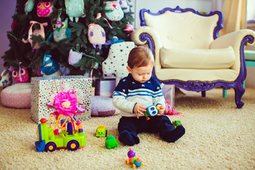 Cute little child is playing with toys while sitting on floor