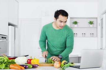 Young man looking recipe on laptop