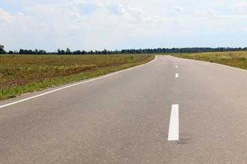 Large grass field in countryside and road