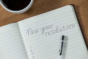 New year resolutions written on diary with coffee mug