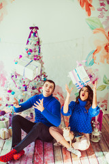 Young couple in blue sweaters plays with present boxes before Ch