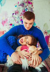 Pretty brunette with red lips leans to chihuahua on man's knees