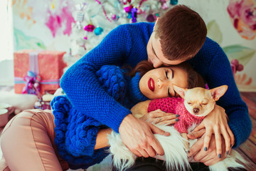 Man in blue sweater kisses tender woman resting on his knees wit