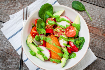 Green salad with spinach, pesto, sweet potato, avocado, radishes, peppers, tomatoes. Love for a healthy raw food concept.