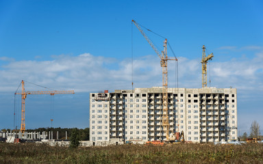 Building crane and apartment house under construction against sky