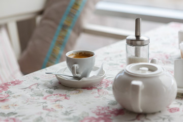 coffee cup and teapot and sugar on a table