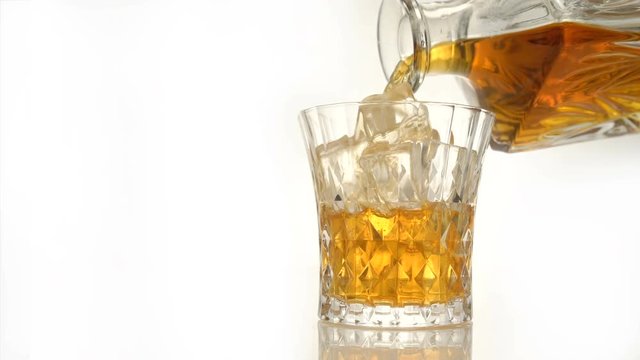 Whiskey on the rocks poured from a rystal decanter on white backround with copy space