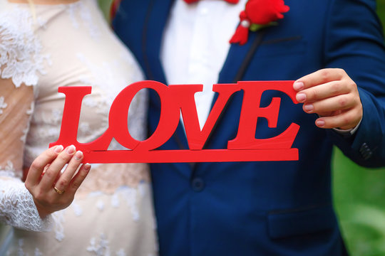 Love text in hands of bride and groom, wedding concept