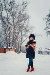 beautiful girl in winter clothes, coat and hat, posing near the church in the , in the snow