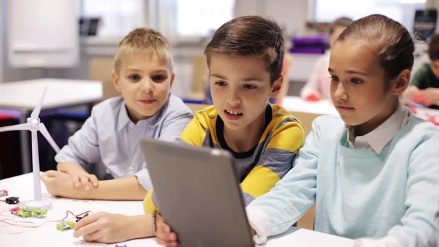 kids with tablet pc programming at robotics school