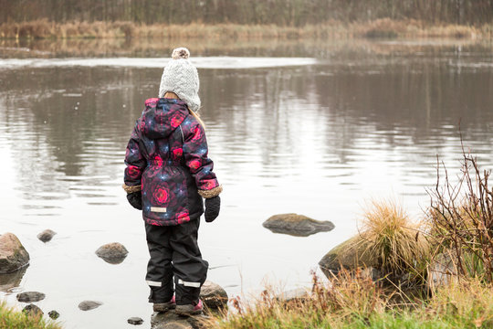 Flicka leker i vattnet i en damm i ett naturreservat
