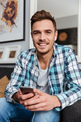 Man holding phone while listening music with earphones