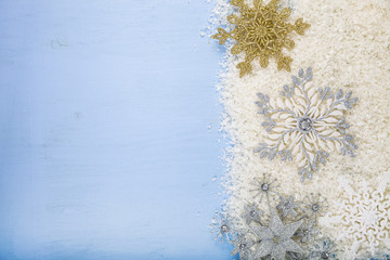 Silver decorative snowflakes and snow on a blue wooden backgroun