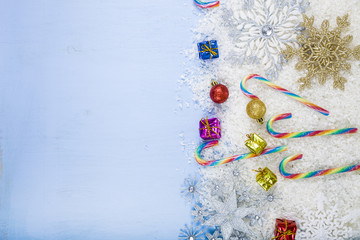 Silver decorative snowflakes and snow on a blue wooden backgroun