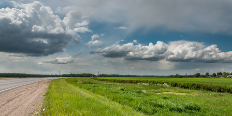 rural landscape. non urban asphalt road, green meadow, beautiful cloudy sky