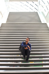 young man with backpack sitting on staircase