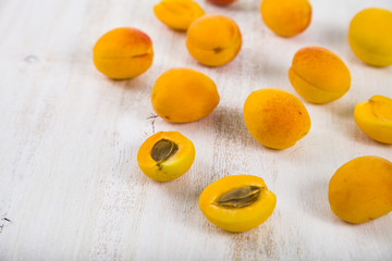 Ripe yellow apricots on a light wooden table close-up.