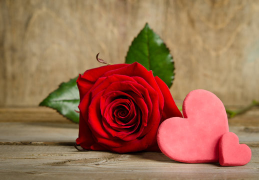 Red rose with handemade valentines around on wooden background