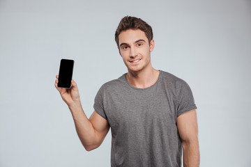 Portrait of a smiling attractive man holding blank screen smartphone