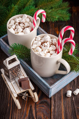 Two cups with small marshmallows on a dark wooden background