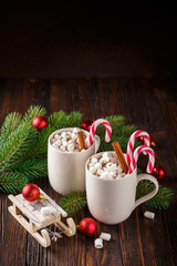 Two cups with small marshmallows on a dark wooden background