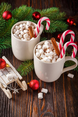 Two cups with small marshmallows on a dark wooden background