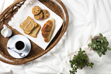 Breakfast Tray Top View / Tray with coffee, croissant, toast, peanut butter and cookies in bad, top view