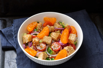 Healthy salad bowl with cuscus, tomatoes, cucumber, chicken, tangerine and sesame seeds