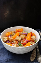 Healthy salad bowl with cuscus, tomatoes, cucumber, chicken, tangerine and sesame seeds