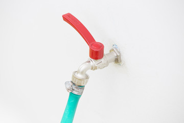 Faucets with hose green on concrete wall.