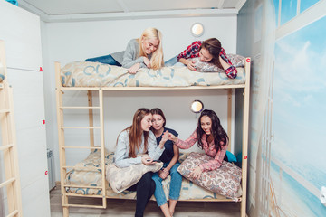 Beautiful girls sitting on a bed in hostel talk and have fun.