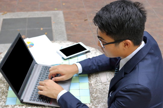 Portrait of handsome businessman using laptop computer for his work at the park outdoors