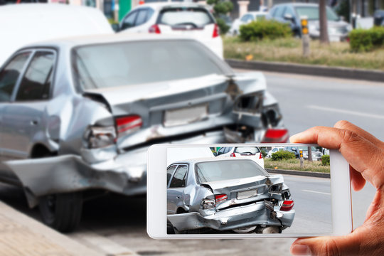 Close up hand holding smartphone and view photo of car accident