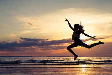 Fototapeta na wymiar Happy girl jumping on the beach at the sunset time