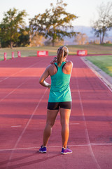 Fototapeta na wymiar Female fitness athelete getting ready to run a sprint race on a tartan athletics track.