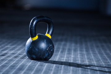 Fototapeta na wymiar Kettle bell weight in a dark gym with moody and edgy lighting