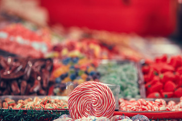 Spiral lolipop surrounded by colorful blur in a candy store