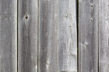 Grayed weathered cedar fencing with knots and cracks.