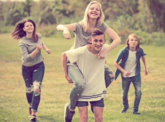 Teenagers running on green lawn in park .