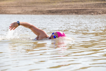 Female triathlete swimming in a dam while competing in a triathlon