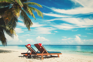 Christmas on beach -chair lounges with Santa hats at sea