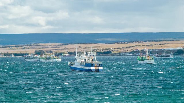Fishing Boats on the Shores of the Port City of Punta Arenas Chile in South America during a Windy Day at Sea with a Landscape Background