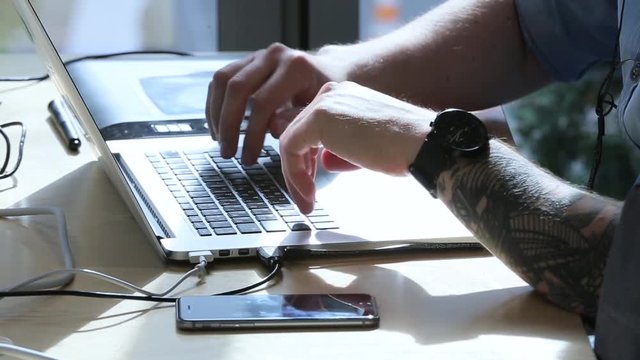 a man with a tattoo is working at a laptop.