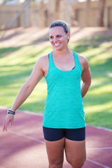 Female fitness model stretching in her warm up before practicing athletics on a tartan athletics track