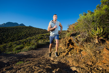 Fototapeta premium Male cross country athlete running in the hills on a warm and su