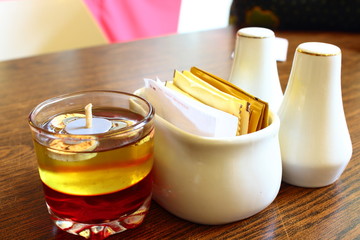 candles, pepper and salt and some sugar packets on restaurant dining table